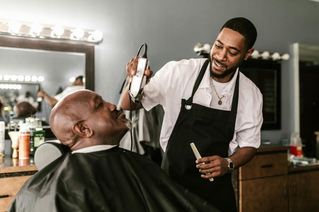 Barber uses clippers and comb to style a client's hair in a relaxed barbershop setting.